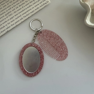 Detail of pink glitter resin mini comb and oval mirror keychain set for bags