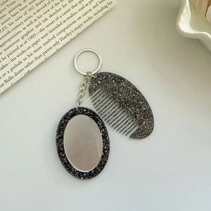 Detail of glitter oval mirror and mini comb keychain set with silver metal hardware