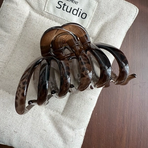 Macro shot of large leopard print hair claw clip on quilted fabric and wood surface