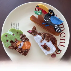 Three acetate hair clips featuring toucan, kangaroo and fox designs in a ceramic plate