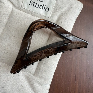 Detail view of triangular leopard print hair claw clip made of resin with metal spring