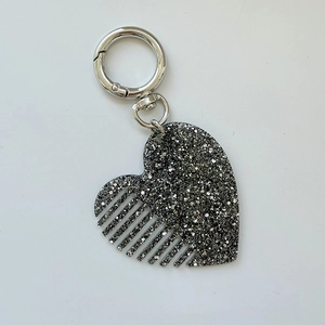 Détail d'un porte-clés peigne en forme de cœur noir avec paillettes argentées