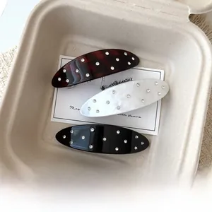 Detail of oval acetate hair clips with rhinestones in tortoiseshell, white and black