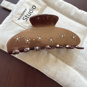 Détail d'une pince à cheveux marron café avec fleurs en cristal sur toile beige