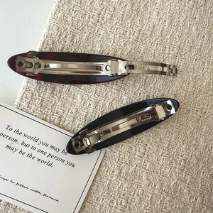 Detail view of oval acetate hair clips with spring closure in tortoiseshell and black