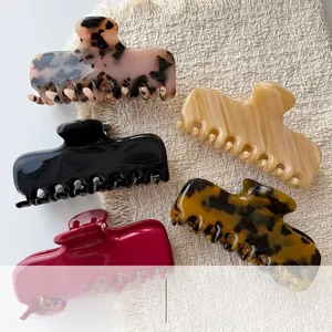 Sortierte Haarklammern aus Acetat mit Leopardenmuster auf beige gestricktem Hintergrund