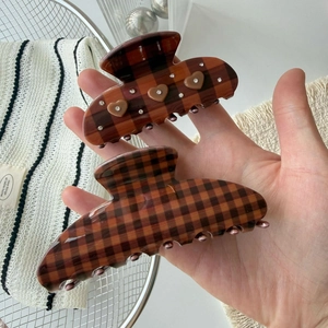 Brown checkered hair claw clip set with heart rhinestones shown in hand for size comparison