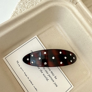 Detailed view of tortoiseshell acetate hair clip with crystal rhinestones on a card