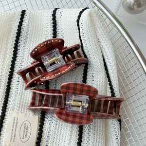 Detailed view of vintage plaid hair claws with sparkling rhinestone edges in brown and red