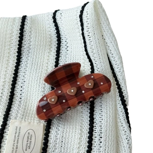 Brown checkered hair claw clip with heart accents and crystals on a soft textile backdrop