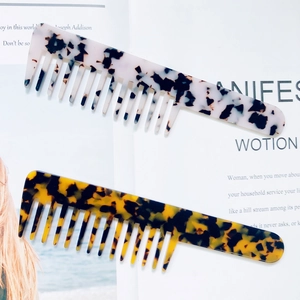 Detail of wide tooth tortoiseshell acetate hair combs in amber and lavender marble patterns