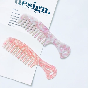 Detail of two wide-tooth acetate combs with marble pattern on a magazine background