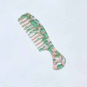 Detail of wide tooth acetate comb featuring green and pink marble floral textures