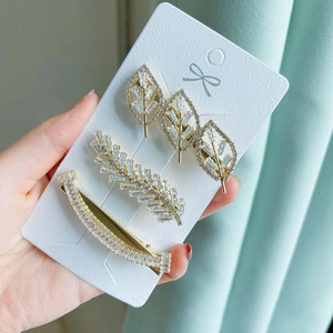 Detailed view of three gold-tone hair clips with rhinestones and elegant leaf designs