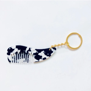 Détail du mini porte-clés peigne en acétate avec motif floral noir et blanc et anneau doré