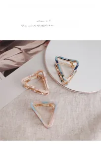 Macro view of triangular acetate hair claws with marble textures and gold metal springs