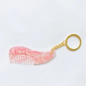 Vue détaillée du porte-clés mini peigne en acétate avec motif de marbre rose et blanc