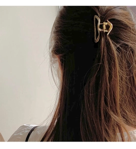 Detail shot of a minimalist gold metal geometric claw clip on brown hair