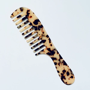 Close-up of wide-tooth acetate hair comb with amber marble texture and smooth handle