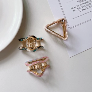 Three acetate hair claws in triangle and wave shapes with marble and tortoiseshell patterns