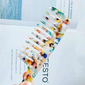 Detailed close-up of a wide-tooth acetate comb with colorful marble texture pattern