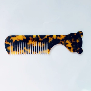 Vue détaillée du peigne à motif écaille de tortue avec manche en silhouette d'ours