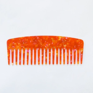 Minimalist wide-tooth acetate hair comb with orange amber marble texture on white background