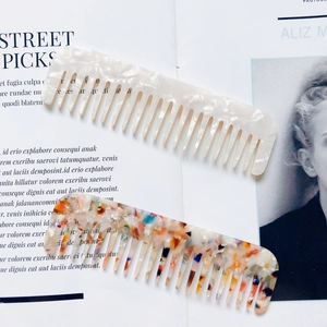 Macro detail of tortoiseshell and pearl white wide-tooth combs on a magazine