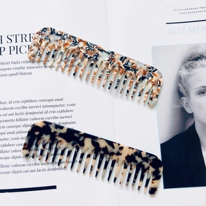 Macro shot of two wide-tooth acetate hair combs with marble and tortoiseshell patterns