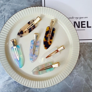 Detail of assorted acetate hair clips with marble patterns and gold metal duckbill clips