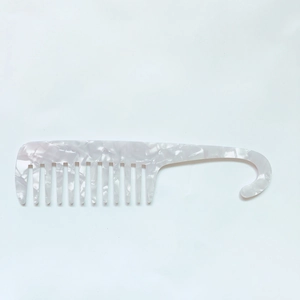Close-up of white marble acetate wide-tooth comb with hook handle for hair detangling