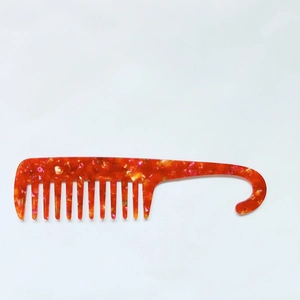 Detail of wide-tooth acetate comb with hook handle and marble texture finish