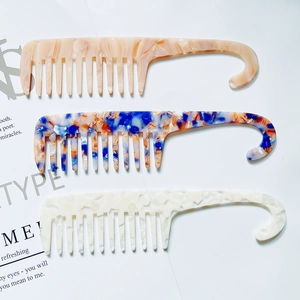 Three acetate wide-tooth hair combs with curved hanging handles in marble patterns