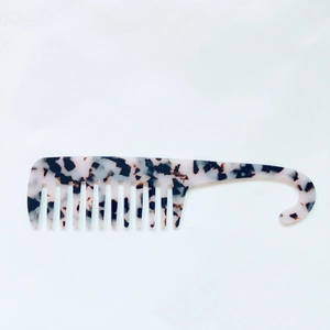 Macro detail of wide-tooth acetate comb with marble texture and hanging hook handle