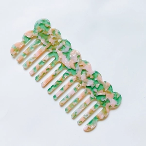 Macro view of green floral cellulose acetate hair comb with wavy edges and smooth teeth