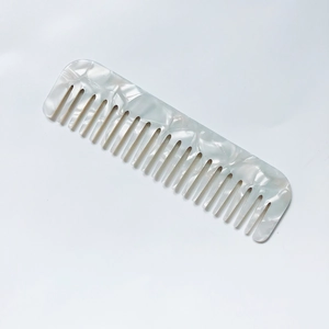 Macro detail of wide-tooth hair comb featuring elegant white and grey marble texture