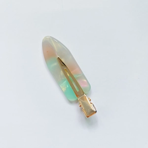 Detail of gradient acetate hair clip with golden metal base and marble texture