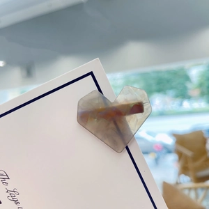 Macro detail of heart-shaped hair clip with marble textured acetate on display card