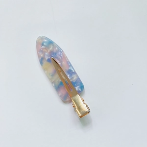 Detail of a pink and blue gradient acetate duckbill hair clip with a gold metal base