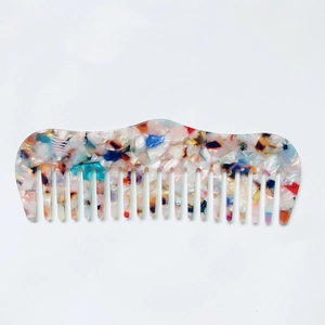 Détail d'un peigne en acétate à motif marbré avec de larges dents lisses sur fond blanc