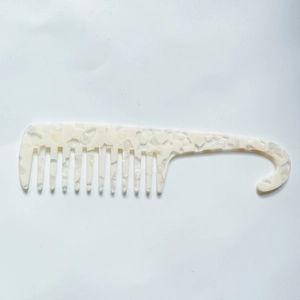 Macro shot of wide tooth acetate comb with pearl marble texture and built-in hanging hook