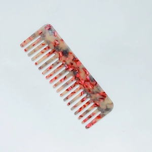 Macro detail of anti-static wide-tooth hair comb with elegant red marble acetate texture