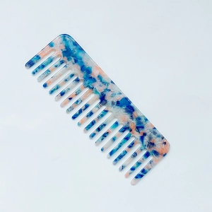 Detail view of wide-tooth acetate comb with blue and pink marble texture pattern