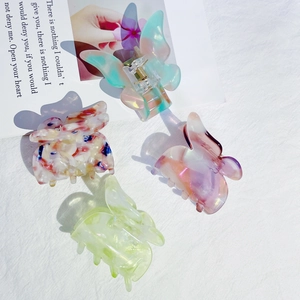 Détail de pinces à cheveux papillon en acétate aux tons pastels sur un tissu blanc doux