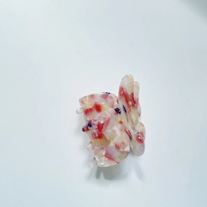 Détail d'une mini pince à cheveux papillon avec texture marbrée en acétate multicolore