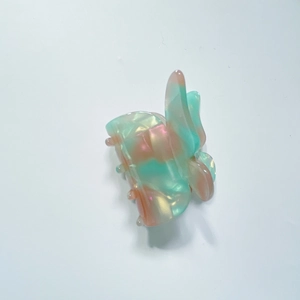 Détail d'une petite pince à cheveux papillon avec texture marbrée vert et rose