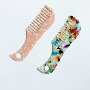 Macro detail of wide-tooth acetate hair combs with marble patterns and hanging holes