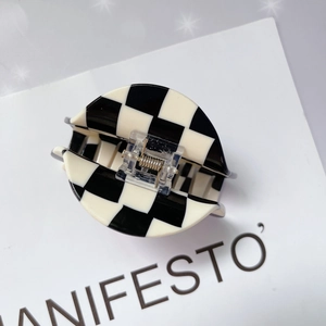 Détail d'une pince à cheveux en acétate à damier noir et blanc avec finition brillante