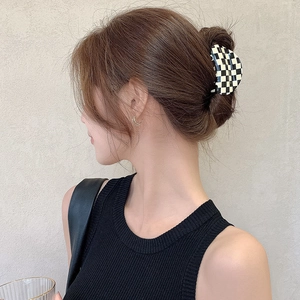 Pince à cheveux classique à damier noir et blanc en acétate sur des cheveux bruns