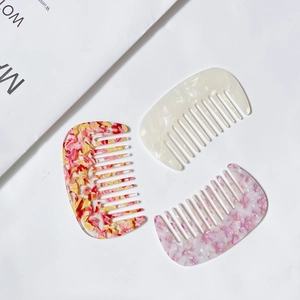 Three-piece set of marble texture acetate hair combs in various colors on white background